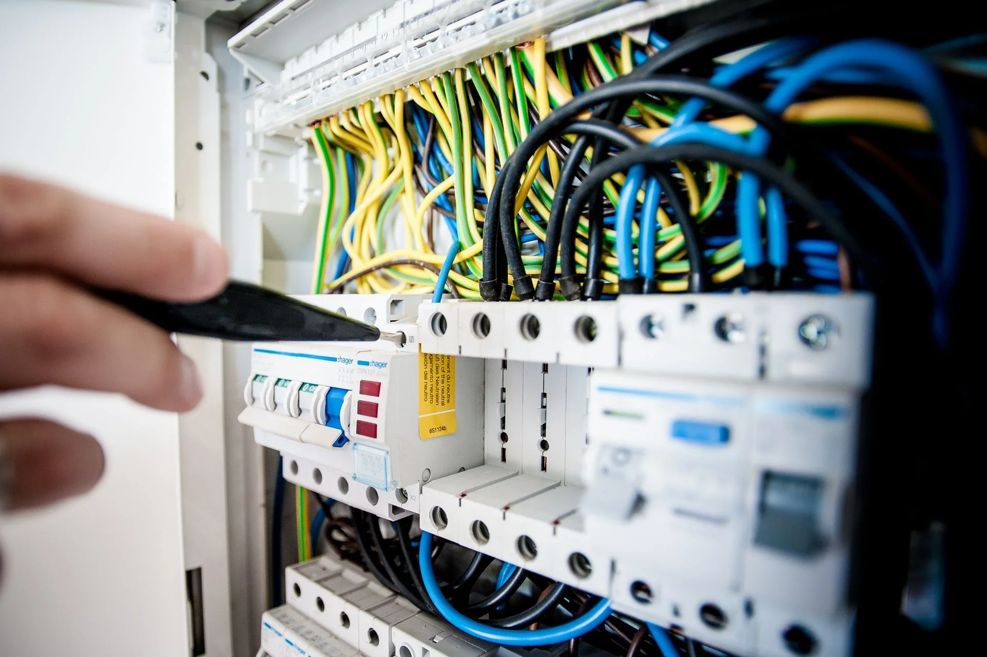 Hands connecting wiring in a circuit breaker panel